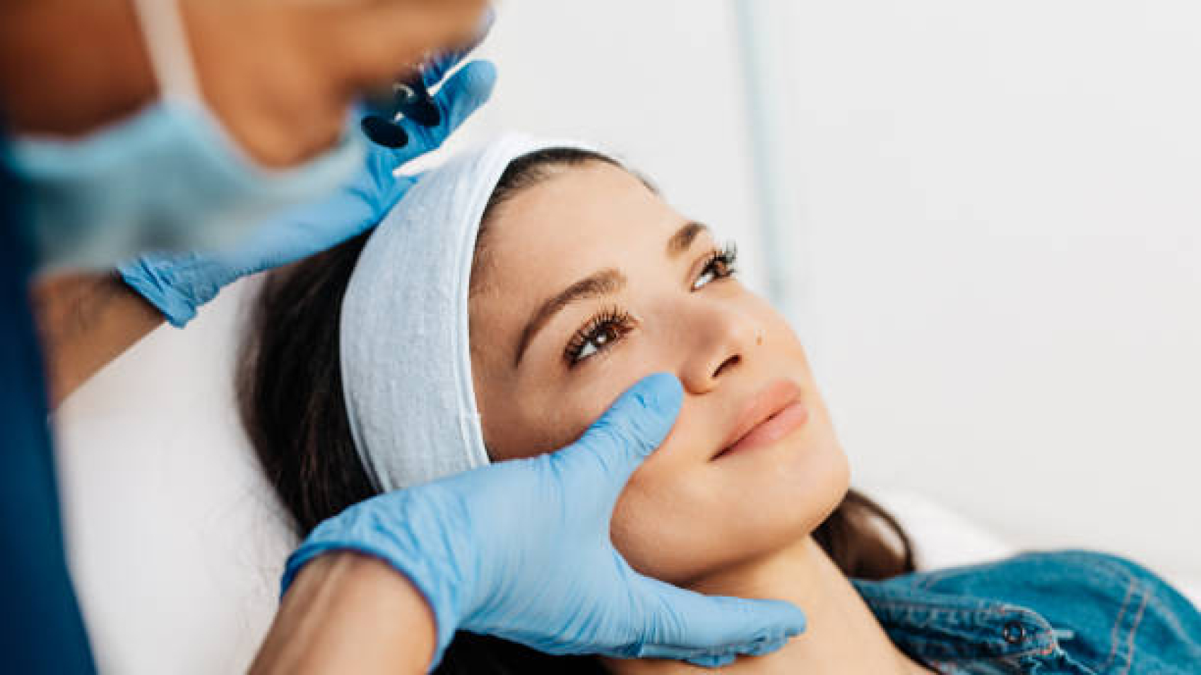 Attractive young woman is getting a rejuvenating facial injections at beauty clinic. The expert beautician is filling female wrinkles by botulinum.