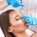 The doctor does injections to correct the hump on the nose. The beautician doeses injections against wrinkles on the face. Women's cosmetology in a beauty salon.