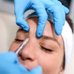 The doctor cosmetologist makes the Rejuvenating facial injections procedure for tightening and smoothing wrinkles on the face skin of a beautiful, young woman in a beauty salon.